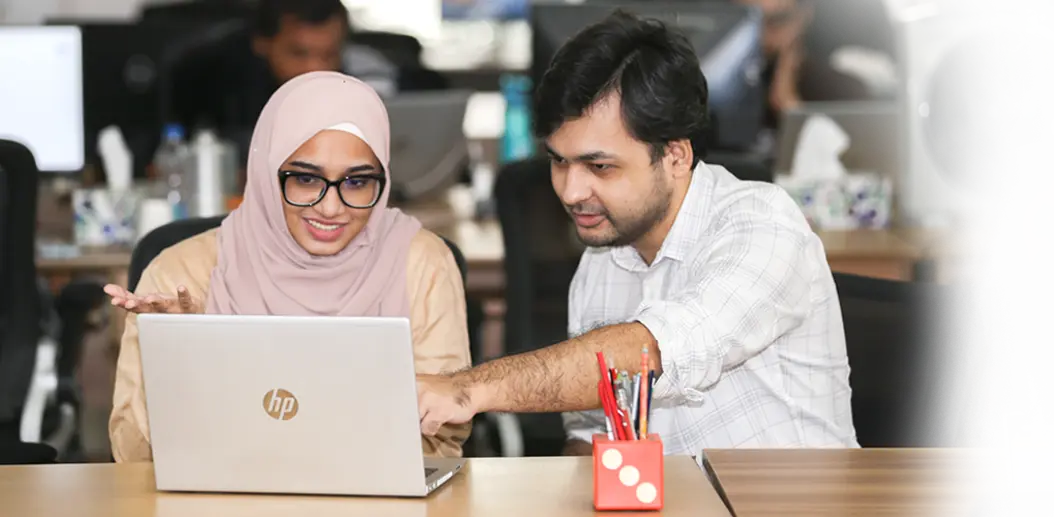 Bright and modern office space with employees smiling and interacting, showcasing a positive work environment.